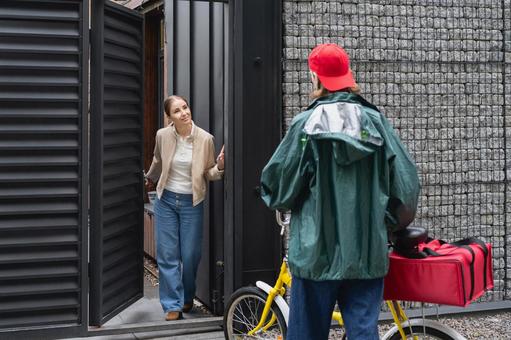 自転車でピザを届けに来たフードデリバリーの男性と家から出てきた女性 配達,フードデリバリー,デリバリーの写真素材