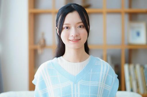 カメラ目線で微笑むベストの女性の写真