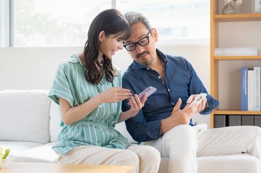 リビングでスマホを見るミドルの夫婦 夫婦,家族,ミドルの写真素材