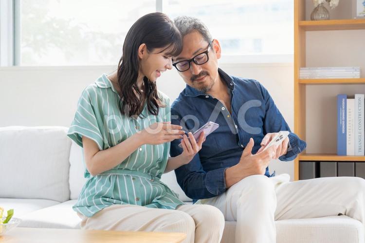リビングでスマホを見るミドルの夫婦 夫婦,家族,ミドルの写真素材