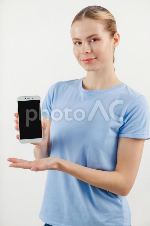 カメラ目線でスマホを持つ女性 スマートフォン,画面,見せるの写真素材