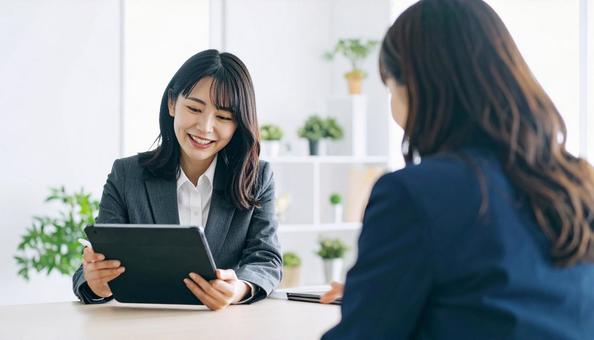 タブレットを使って説明する女性営業マン タブレットを使って説明する女性営業マンの写真