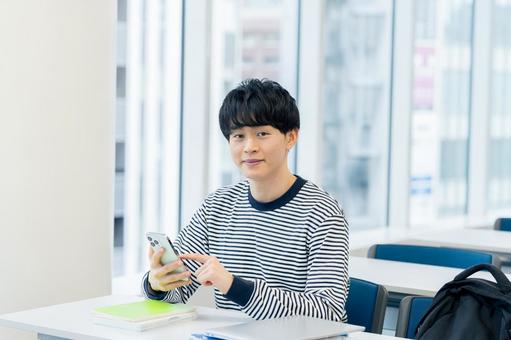 教室でスマホを見る大学生 スマホ,笑顔,大学生の写真素材