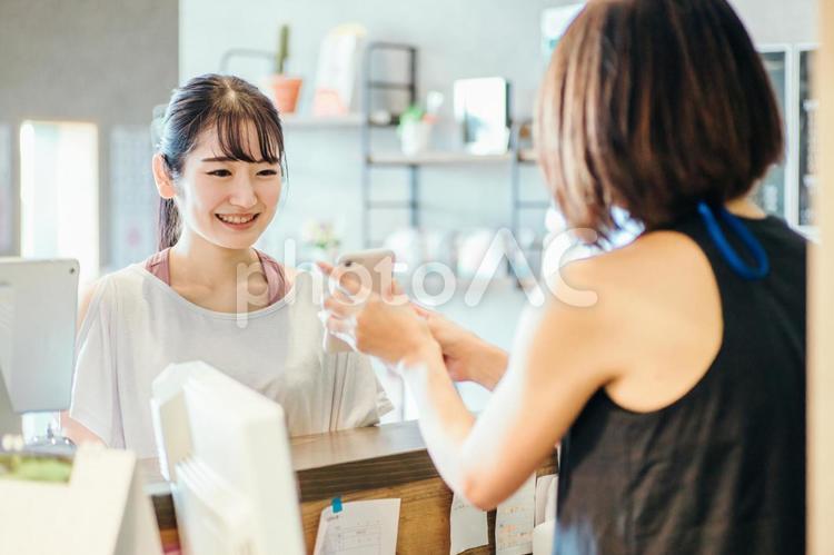 受付でスマホを出す女性 スマホ,受付,ポイントの写真素材