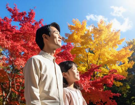 青空の下で秋の紅葉を仲良く鑑賞する親子 青空の下で秋の紅葉を仲良く鑑賞する親子の写真