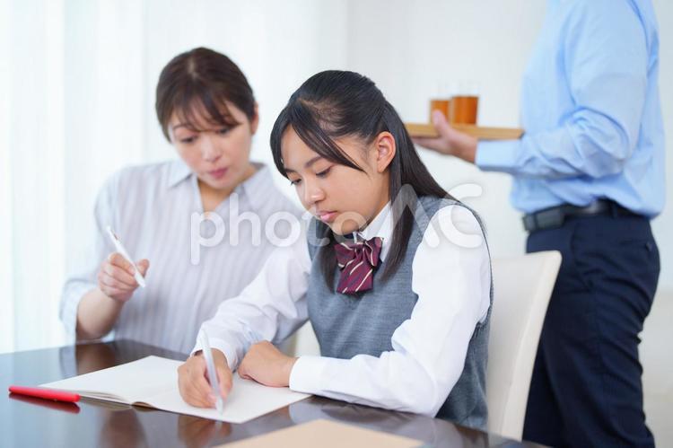 家庭教師と勉強する女子生徒とお茶を運ぶお父さん 人物,女の子,女子生徒の写真素材