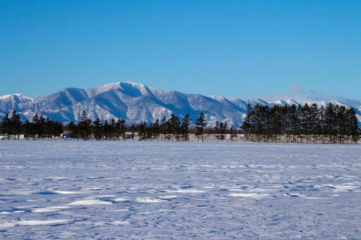 日高の山並みと冬の牧場 日高の山並みと冬の牧場の写真