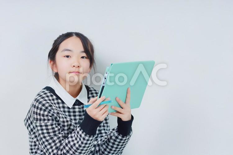 タブレットを持ったカメラ目線の小学生 女性,小学生,少女の写真素材
