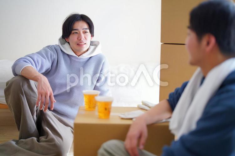 引っ越しの合間にビールを飲みながら話す2人の男性 引っ越し,一人暮らし,男性の写真素材