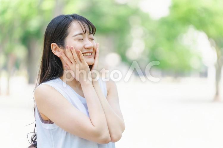 新緑の中でスキンケアする笑顔の日本人女性 美容,女性,自然の写真素材
