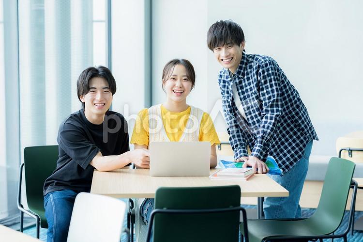 パソコンを見ながら話す学生たち 大学生,笑顔,学校の写真素材