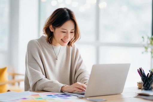 明るい部屋でノートパソコンで作業する女性 明るい部屋でノートパソコンで作業する女性の写真