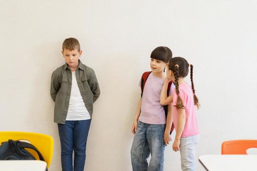 内緒話する女の子と壁にもたれる男の子 男の子,女の子,子どもの写真素材