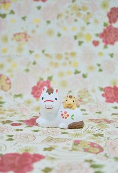 可愛い馬の置物と和柄の背景の年賀状素材の写真