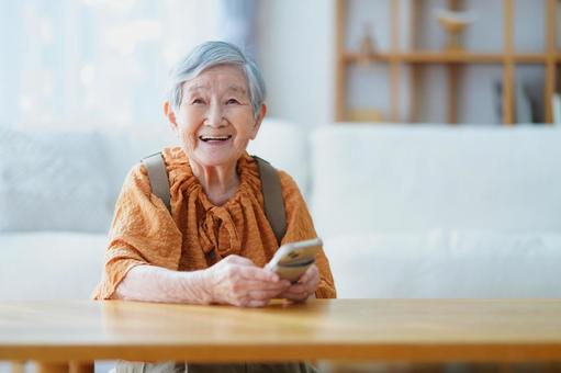 スマホを持ち笑う高齢女性 女性,スマートフォン,持つの写真素材