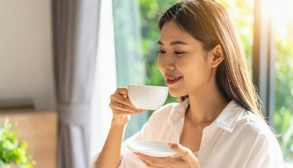 カフェでホットコーヒーを飲む女性 カフェでホットコーヒーを飲む女性の写真