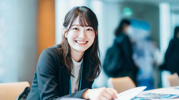 企業ブースで説明する笑顔の女性社員 企業ブースで説明する笑顔の女性社員の写真