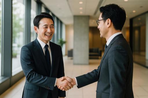 同僚と握手する社員 同僚と握手する社員の写真