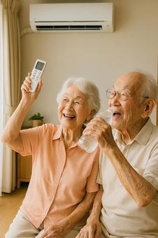 エアコンをつけて水分補給をする高齢夫婦④ エアコンをつけて水分補給をする高齢夫婦④の写真