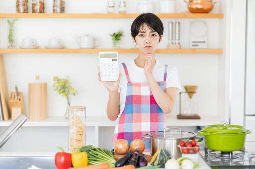 電卓を持って悩む主婦。 電卓を持って悩む主婦。 主婦,キッチン,悩みの写真素材