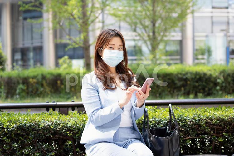 マスクをしてスマホを見る女性 女性,スーツ,olの写真素材