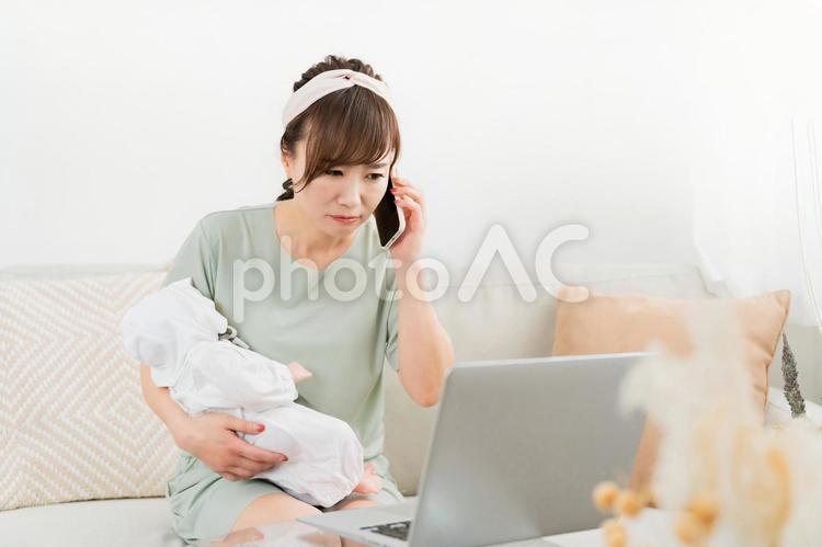 赤ちゃんを抱きながらスマホで電話する女性 赤ちゃん,パソコン,電話の写真素材