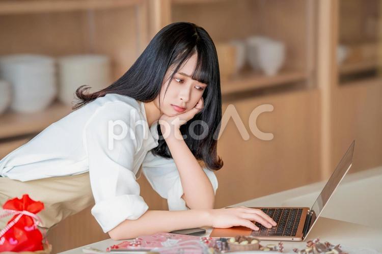 難しい顔で料理方法を調べるエプロン姿女性 バレンタイン,バレンタインデー,チョコの写真素材