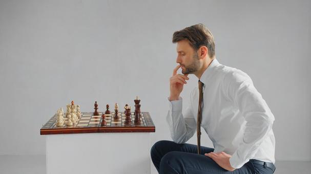 チェスしながら考えている横向きの男性(グレー背景) チェスしながら考えている横向きの男性(グレー背景)の写真