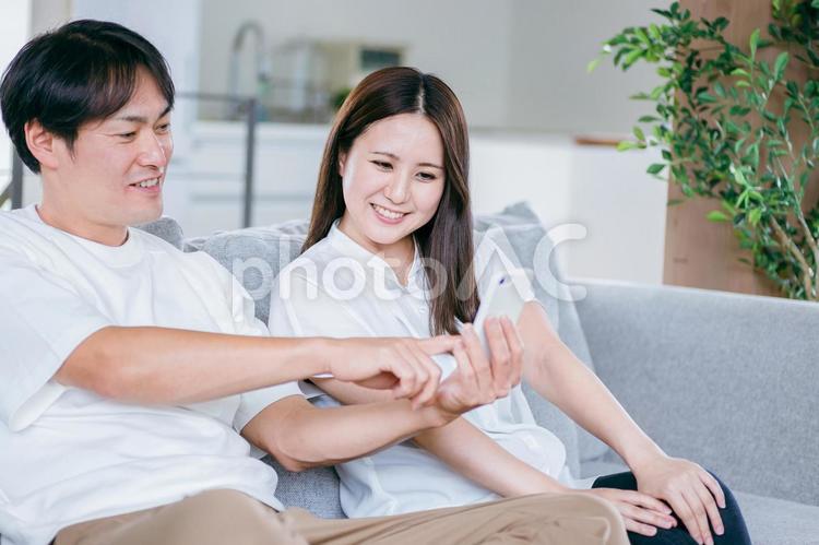 部屋でスマホを使う男女 スマホ,夫婦,アプリの写真素材