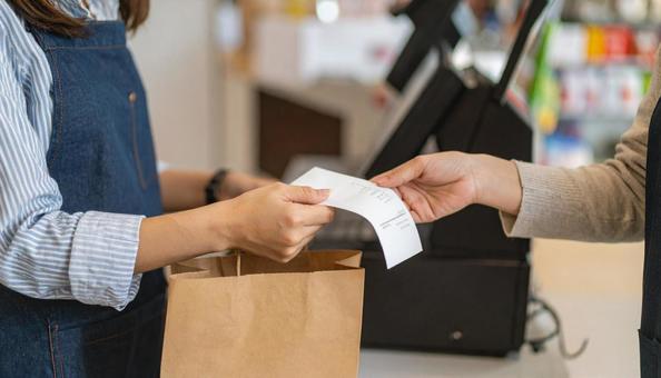 レジでレシートとおつりをもらう女性の手の写真