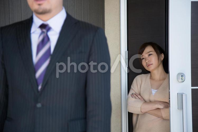 玄関で夫を送り出す妻（妻にピント） 夫婦,疑う,嘘の写真素材