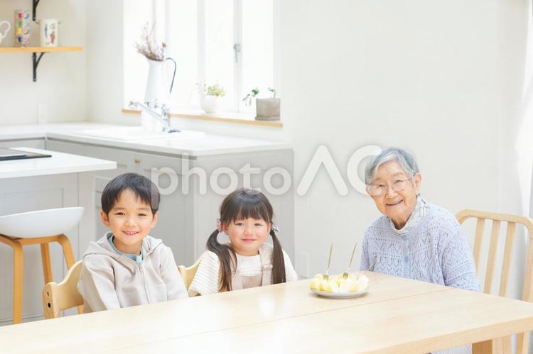 ダイニングで座っているカメラ目線のおばあちゃんとひ孫たち おばあちゃん,ひいおばあちゃん,男の子の写真素材