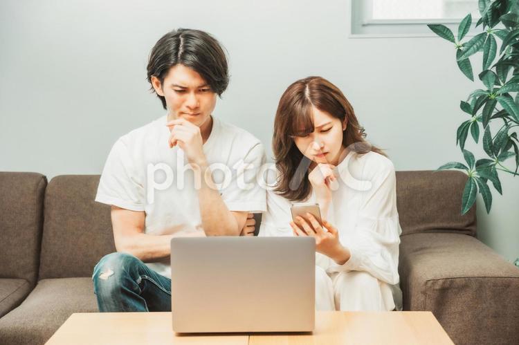 ノートパソコンとスマホを使う男女（困る） ノートパソコン,スマホ,困るの写真素材