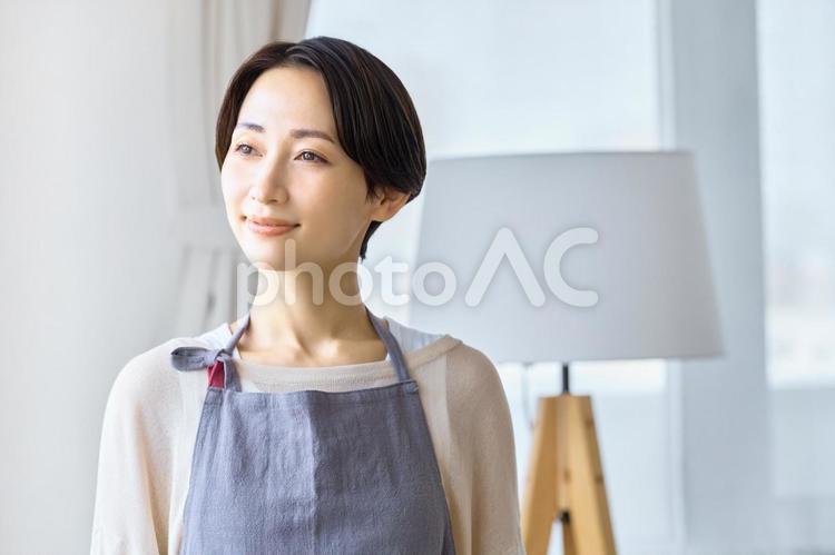 遠くを見る主婦　エプロン　部屋 主婦,リビング,笑顔の写真素材