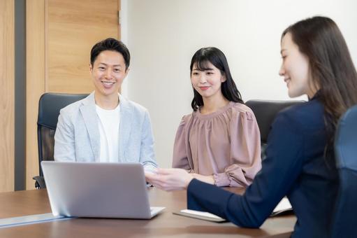 若い夫婦と商談をするセールスマン 若い夫婦と商談をするセールスマン セールスマン,会議,ビジネスの写真素材