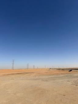 青空の下、砂漠に続く鉄塔と道路 青空の下、砂漠に続く鉄塔と道路の写真