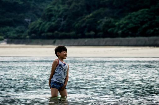 <素材>夕暮れの海で水遊びをする男の子” <素材>夕暮れの海で水遊びをする男の子”の写真