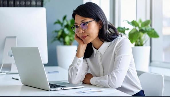 パソコンの前で考える女性社員 パソコンの前で考える女性社員の写真