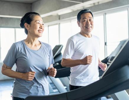 ランニングマシンで走る仲良しシニア夫婦 ランニングマシンで走る仲良しシニア夫婦の写真