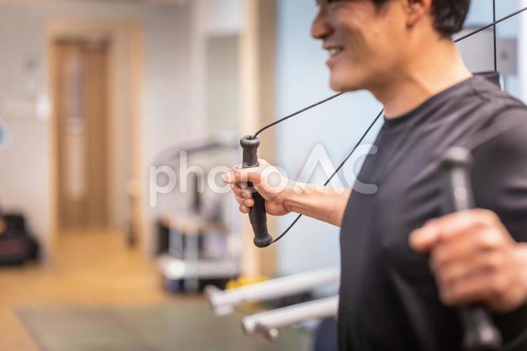 スポーツジムでケーブルマシンを使う男性 ケーブルマシン,ケーブル,ワークアウトの写真素材