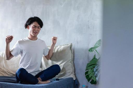 ベッドで伸びをする若い男性 スッキリ,クッション,観葉植物の写真素材