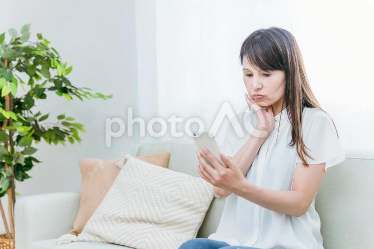 ソファに座るミドル世代の女性（困る） スマホ,アプリ,スマートフォンの写真素材