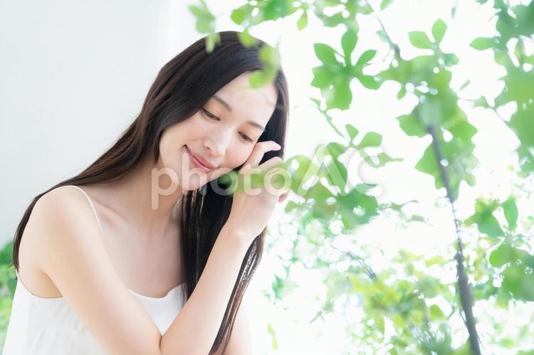 緑の中でスキンケアをする若い女性 ビューティー,女性,スキンケアの写真素材