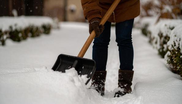 大雪が降った日の翌日の朝に雪かきする女性 大雪が降った日の翌日の朝に雪かきする女性の写真