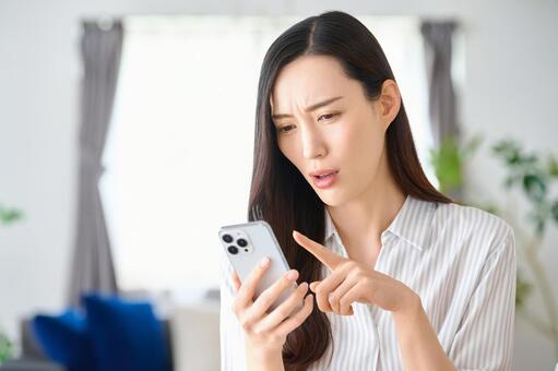 スマートフォンを見て困った表情の女性 女性,スマートフォン,困るの写真素材