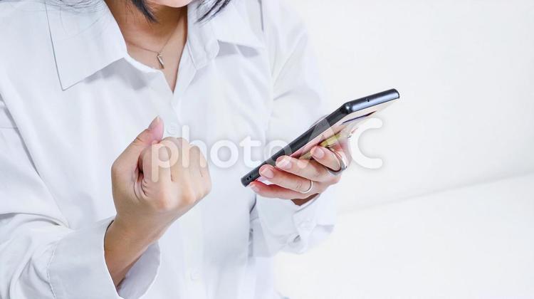 スマホを見てガッツポーズをする人 勝利,スポーツ観戦,優勝の写真素材