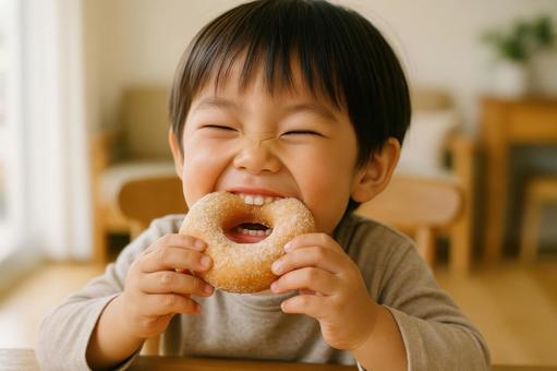 ドーナツを頬張る子どもの笑顔 ドーナツを頬張る子どもの笑顔の写真
