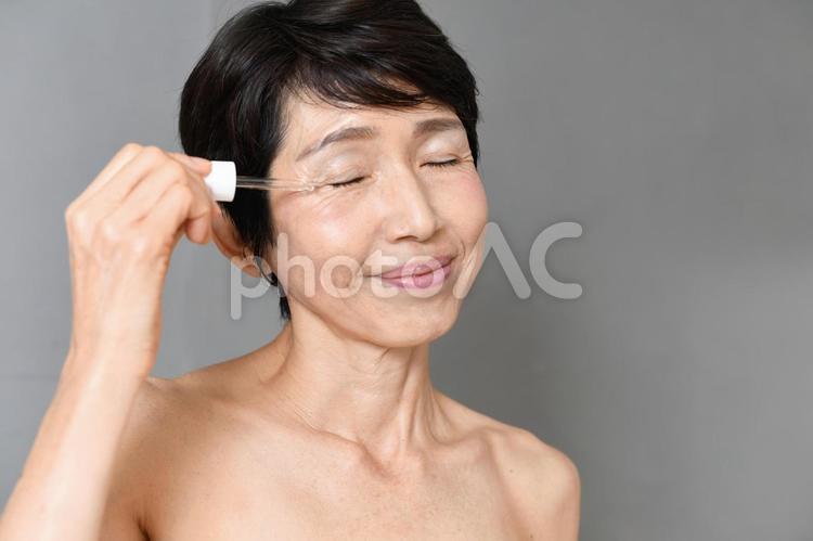 スポイドで美容液を顔につける中年女性 美容液,保湿,中高年の写真素材