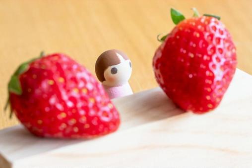 A small doll looking up at a strawberry, JPG
