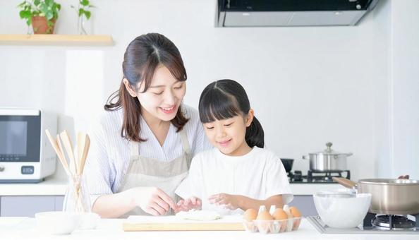 キッチンで楽しそうに料理をする母娘の写真